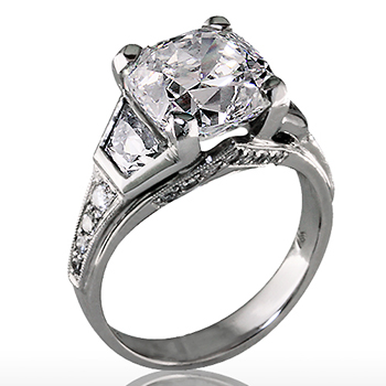 Style: ER433 A large round center diamond bookended with two trapezoid diamonds and embellished with round brilliant cut diamonds on the sides.